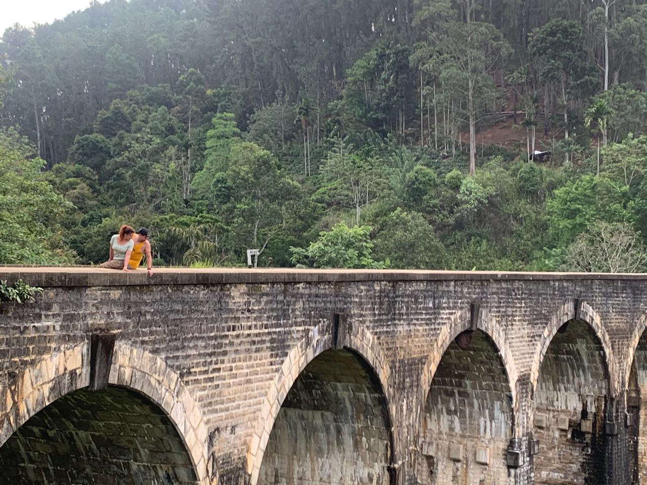 Voyageurs assis sur le pont aux Neuf Arches à Ella, viaduc colonial dans la jungle